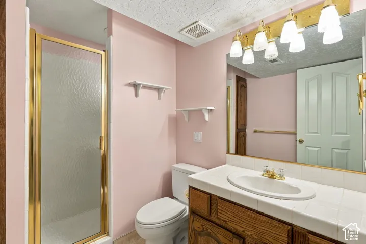 Vanity with wood-finish cabinetry, tile countertop, and an integrated oval sink with a gold-tone faucet