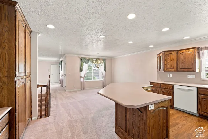 Kitchen featuring wood cabinetry, a built-in dishwasher, and a peninsula with countertop seating
