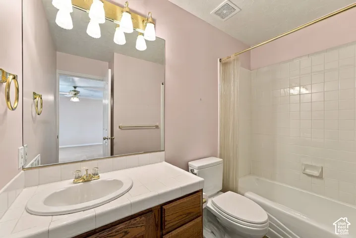Bathroom featuring a white tile vanity with an integrated sink, wood-finish cabinetry, and a large wall-mounted mirror
