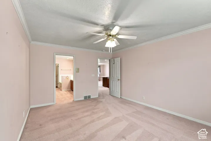 Wall-to-wall carpeting, ceiling fan with integrated lighting, and crown molding
