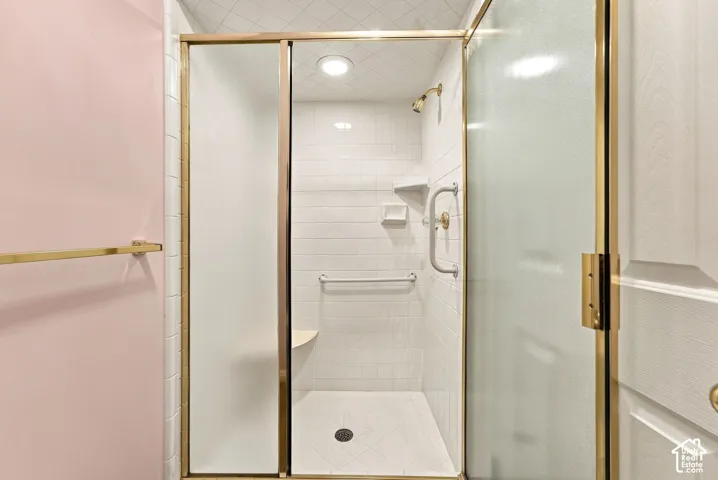 Tiled shower enclosure featuring a built-in bench, gold-tone fixtures, and grab bars