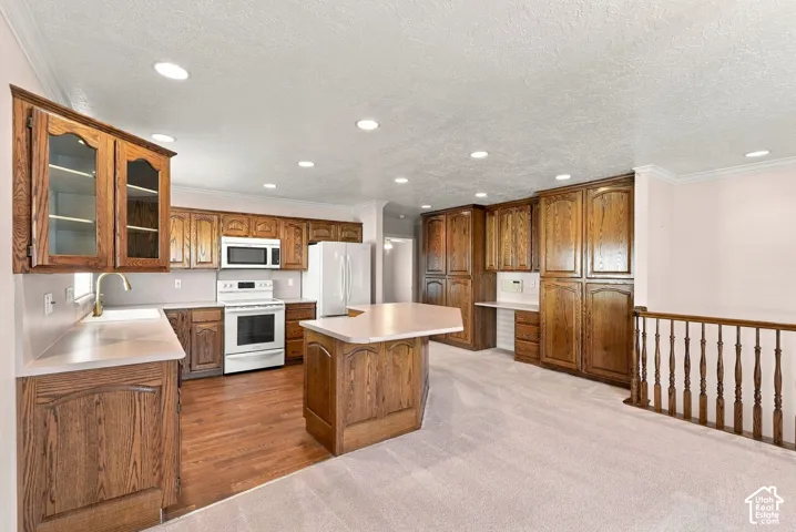 Spacious kitchen featuring extensive wood cabinetry, white appliances, a central island, and recessed lighting