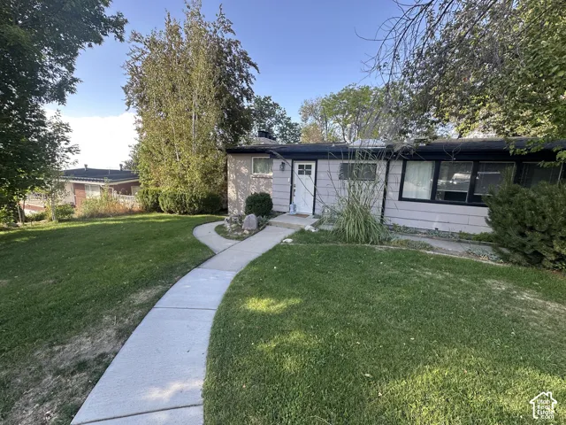 Exterior featuring a concrete walkway, mature trees, and a front entry door with a window