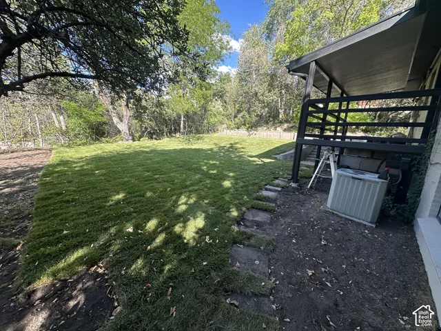 Expansive lawn area, shaded by mature trees, features a stone paver pathway
