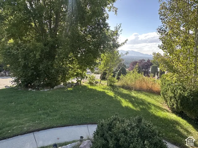 Expansive lawn with mature trees and established landscaping, offering a mountain backdrop and distant scenery