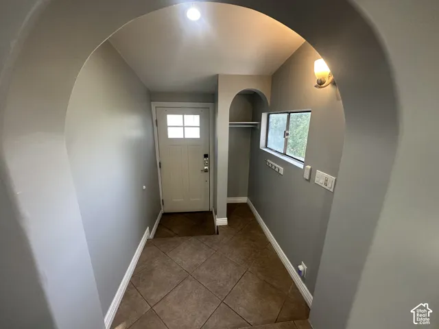 Archway entry featuring tile flooring, a paneled front door with upper lites, and an integrated wall niche with a hanging rod