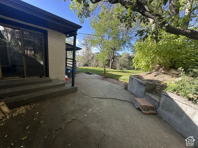 Exterior patio with light brick siding, dark-framed sliding glass doors, and a covered porch
