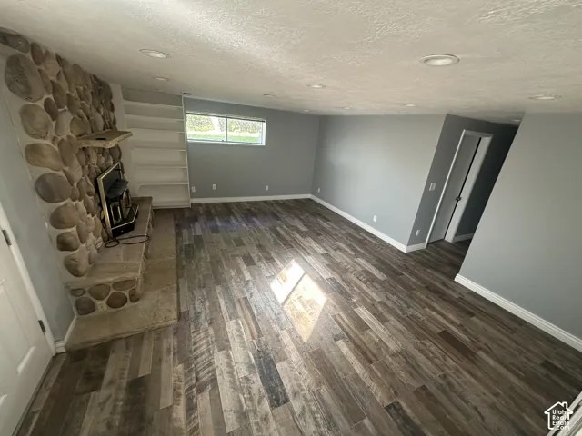 Stone-clad fireplace with hearth, built-in shelving, recessed lighting, and wood-finish flooring