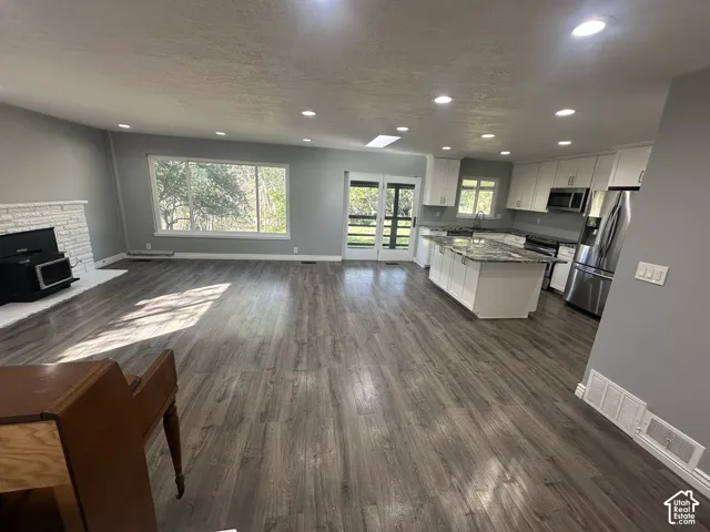 Open concept living space with wood-finish flooring, recessed lighting, and a white brick fireplace