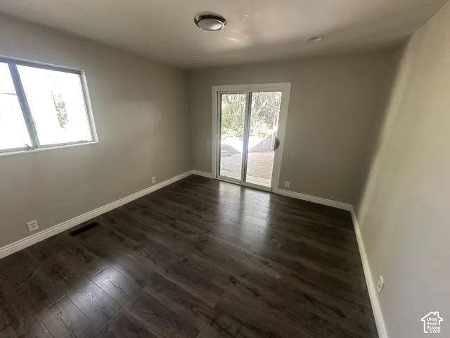 Wood-finish flooring with white baseboards, sliding glass door, and a single window