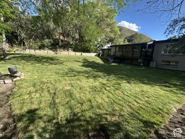 Expansive backyard featuring a manicured lawn, established trees, and a multi-level deck