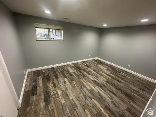 Recessed lighting illuminates the room, featuring gray walls, wood-finish flooring, and crisp white trim