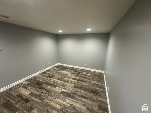 Recessed lighting, wood-finish flooring, light grey painted walls, and white baseboards