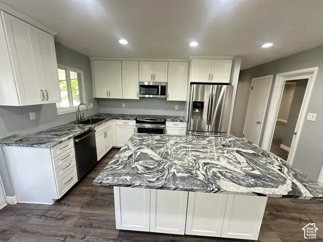 Kitchen featuring white shaker cabinetry, patterned countertops, stainless steel appliances, and wood-finish flooring