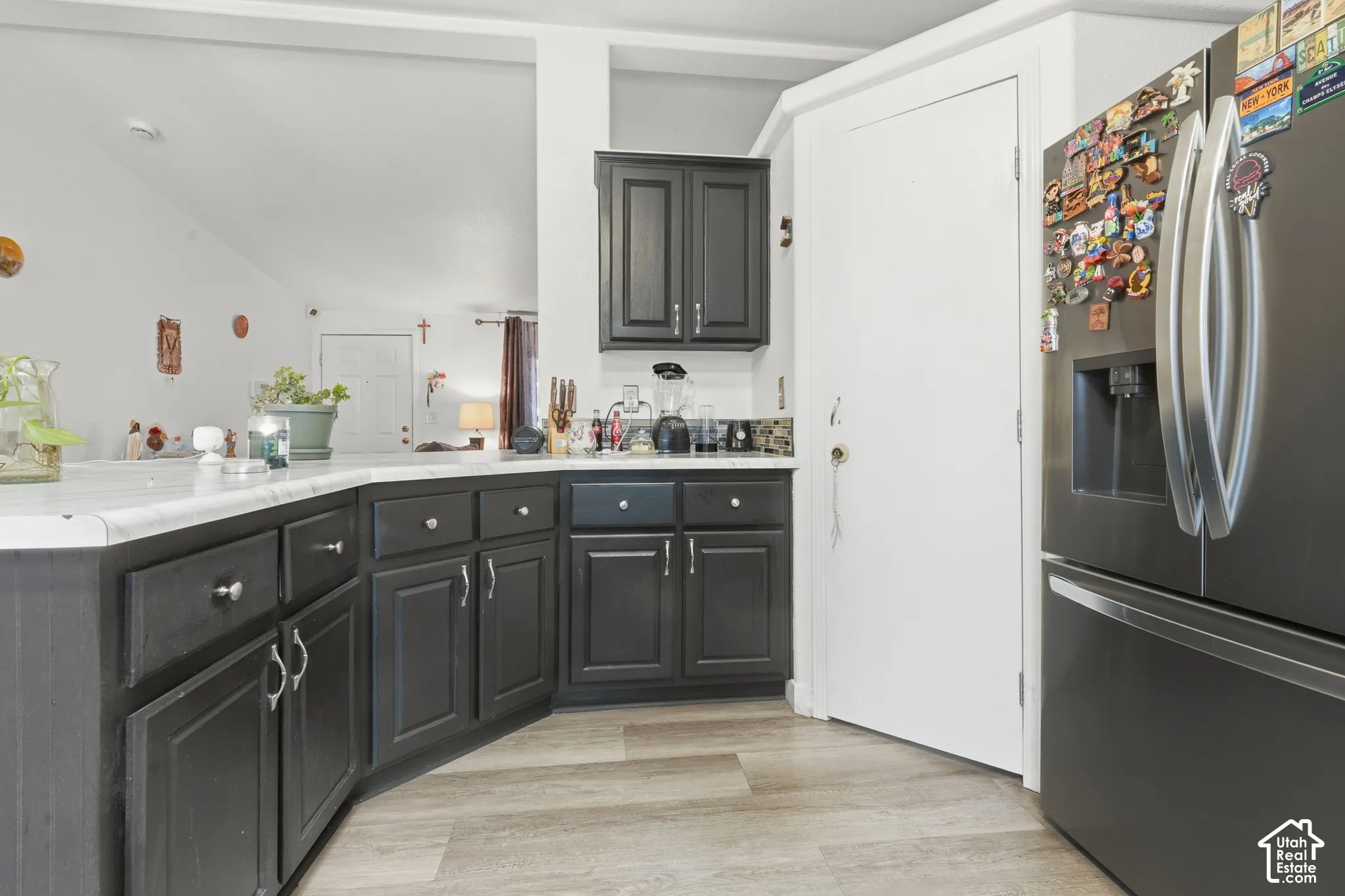Dark-toned cabinetry with silver-toned hardware, light-toned countertops, and wood-finish flooring