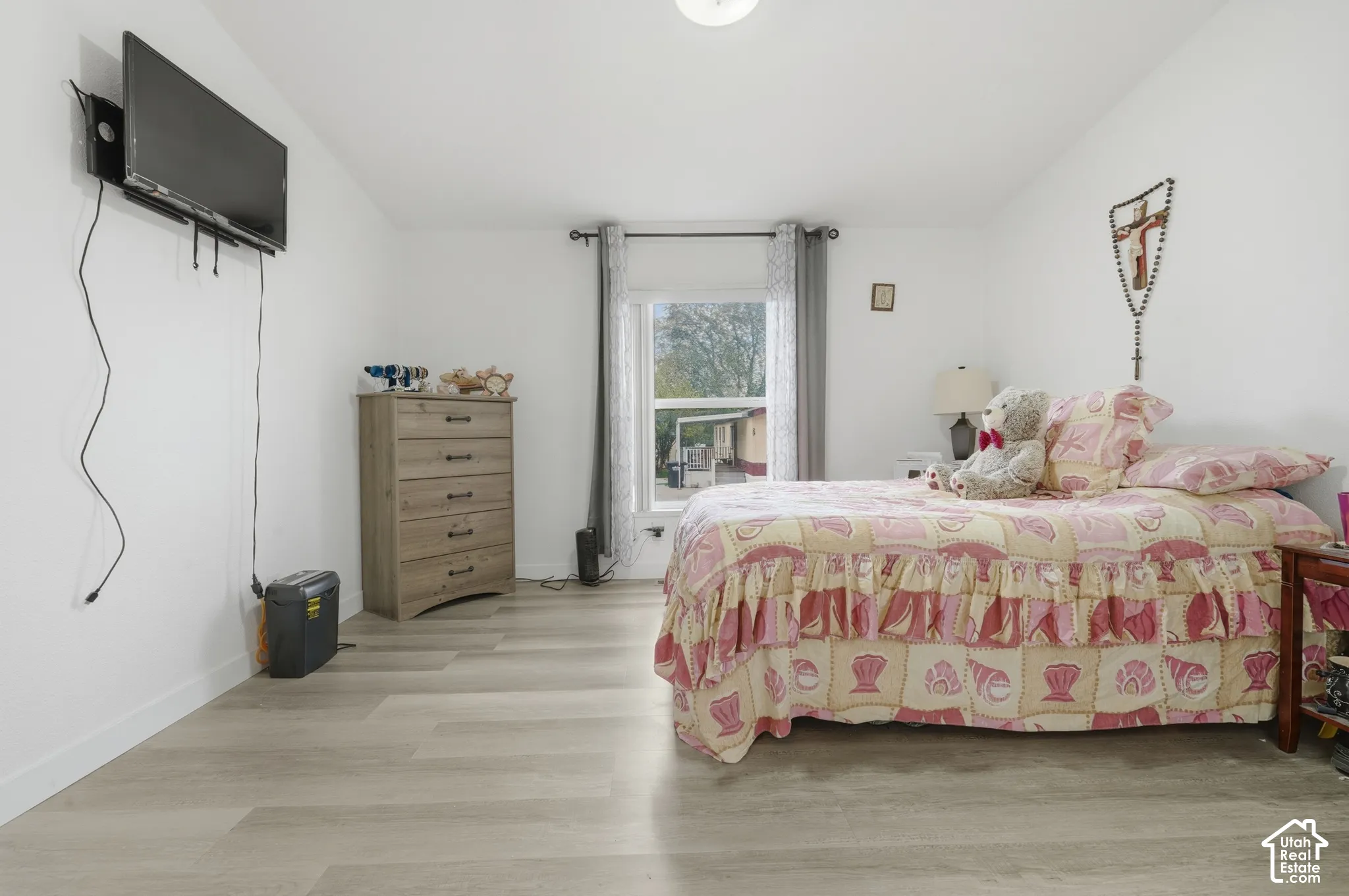 Light-toned wood-finish flooring, white painted walls, and a ceiling-mounted light fixture
