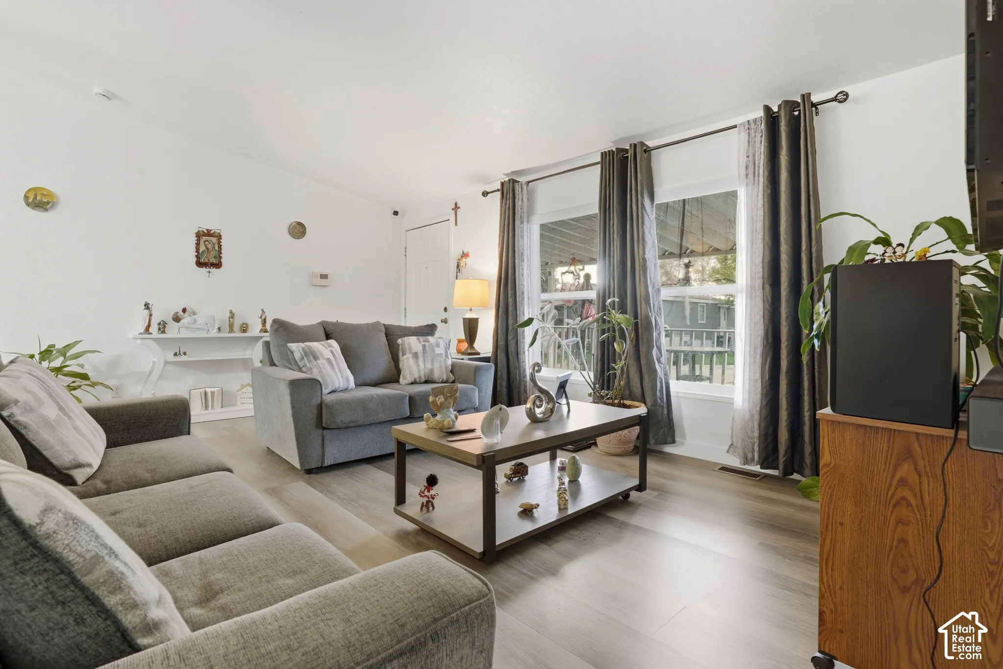 Spacious living area featuring light wood-finish flooring, vaulted ceilings, and white wall finishes