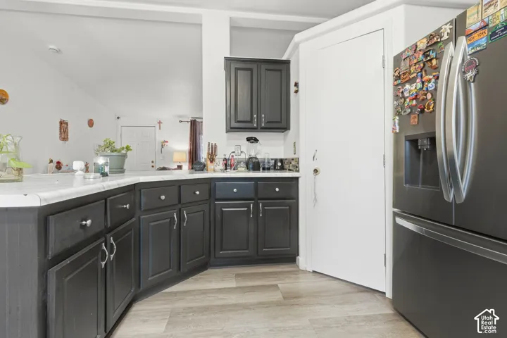 Dark-toned cabinetry with silver-toned hardware, light-toned countertops, and wood-finish flooring