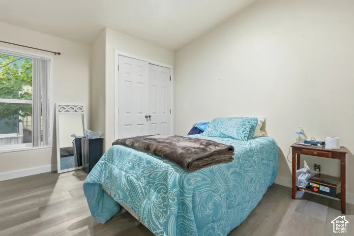 Wood-finish flooring, white paneled double closet doors, and an operable window