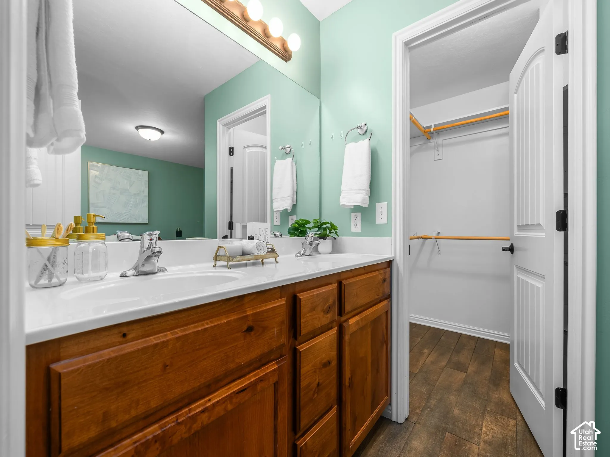 Dual vanity with white undermount sinks, wood-finish cabinetry, and full-width mirror