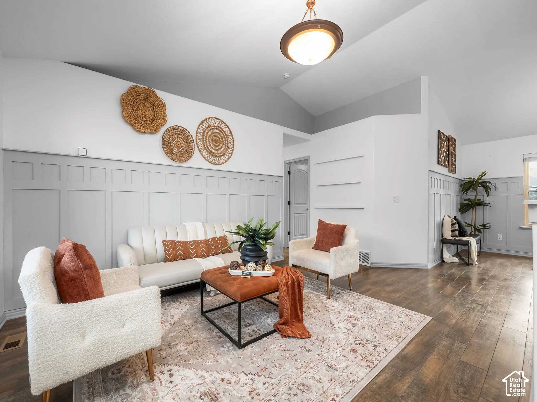 Vaulted ceiling, paneled accent walls, recessed wall shelving, and wood-finish flooring