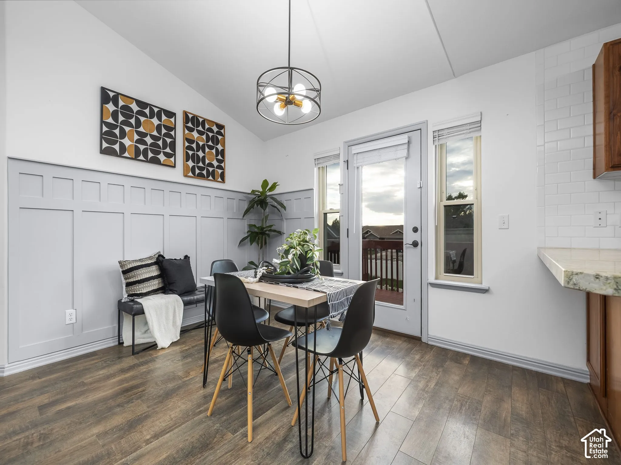 Bright dining area featuring wood-finish flooring, wainscoting accent wall, and pendant lighting