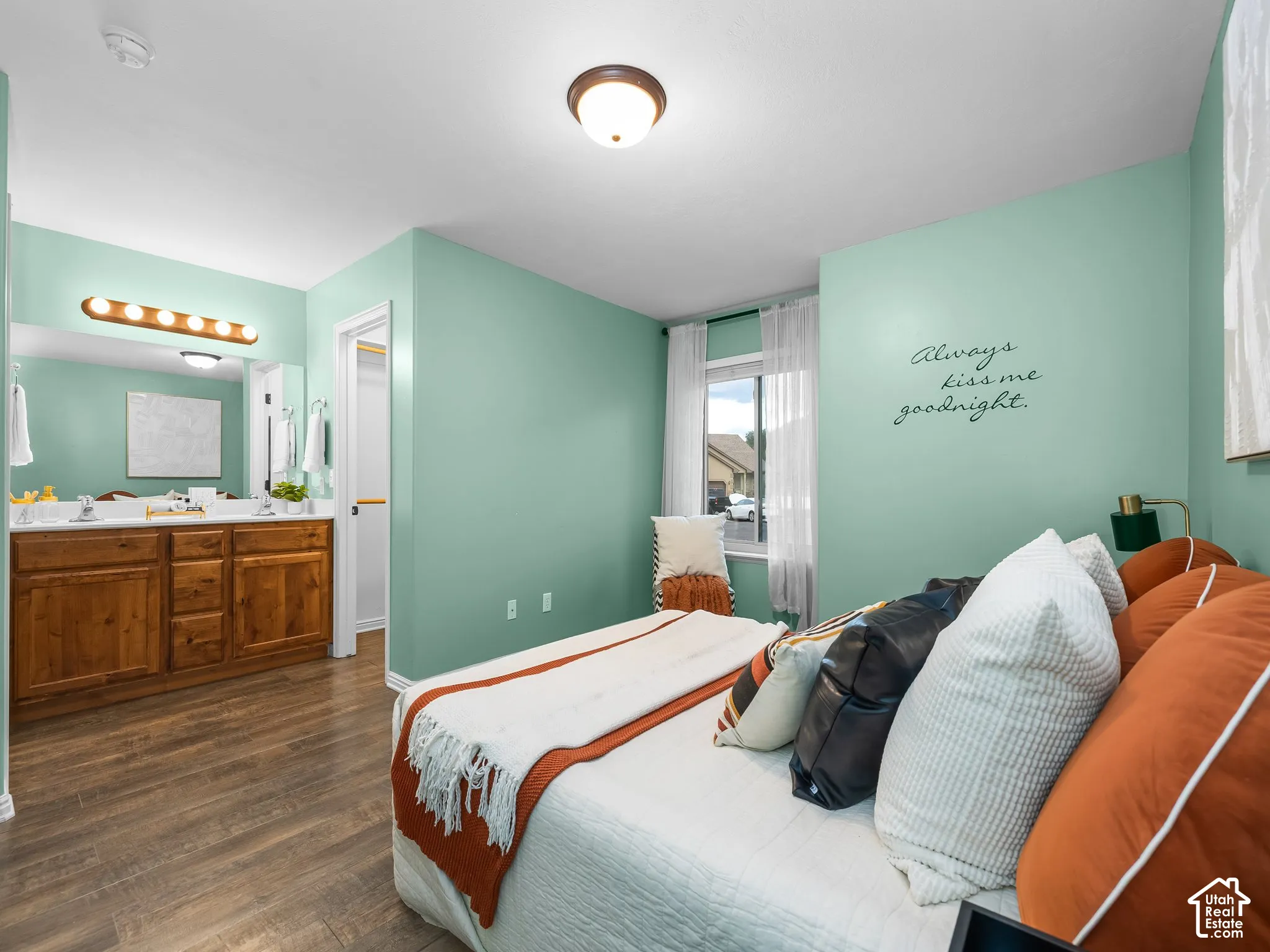 Wood-finish flooring throughout, dual vanity with wood cabinetry, and a window with natural light