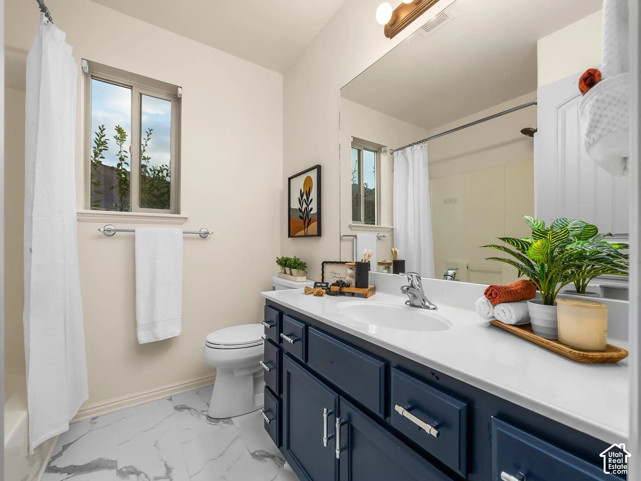 White vanity countertop with an integrated sink, dark blue cabinetry, and chrome hardware