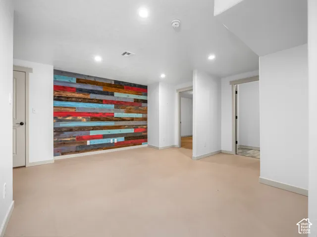 Accent wall featuring colorful wood paneling, recessed ceiling lighting, and smooth flooring