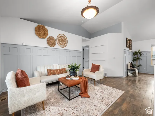 Vaulted ceiling, paneled accent walls, recessed wall shelving, and wood-finish flooring