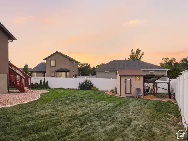 Expansive lawn area, white vinyl fencing, built-in exterior staircase, and a detached shed structure