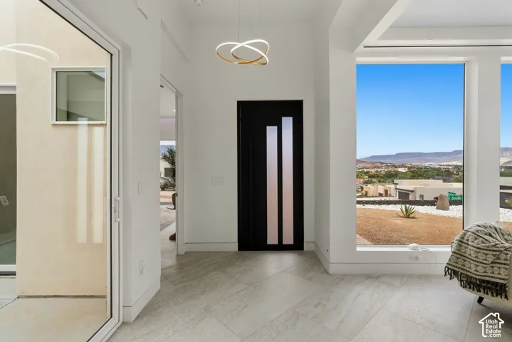 Large format tile flooring, black entry door with vertical glass inserts, recessed ceiling, large picture windows, and a contemporary ceiling light fixture