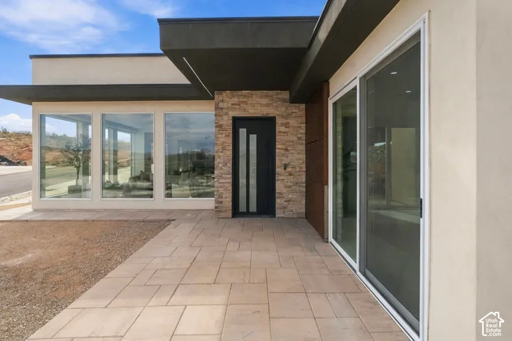 Modern exterior featuring stacked stone accents, a flat roofline, floor-to-ceiling windows, a contemporary entry door, and a tiled walkway