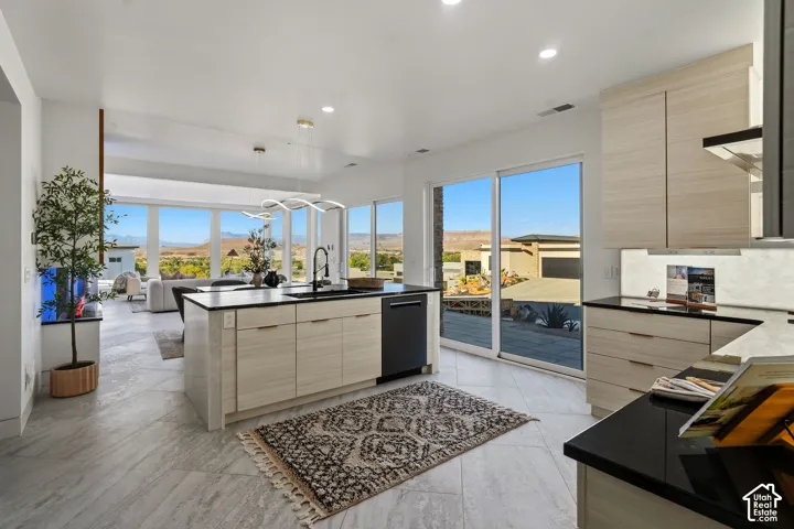 Contemporary kitchen featuring light wood-finish cabinetry, dark countertops, and integrated appliances