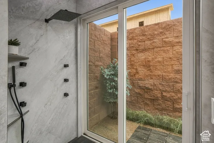 Tile-surrounded shower with a rainfall showerhead, multiple body jets, and a handheld spray wand