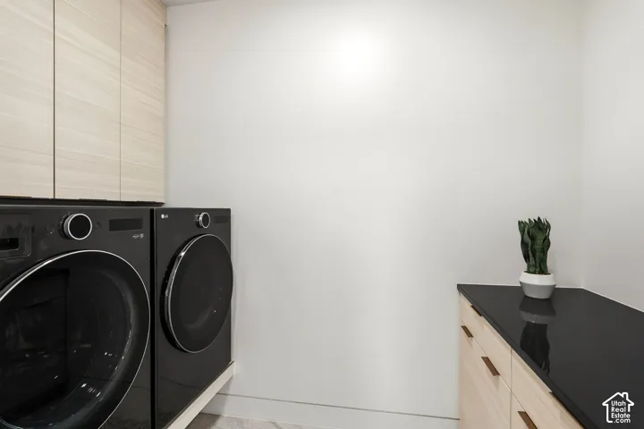 Built-in cabinetry with wood-finish doors, black countertop, and a front-load washer and dryer set