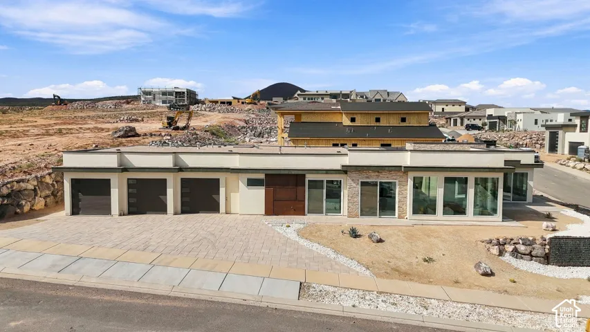 Modern exterior with a light-colored stucco finish, stone veneer accents, and multiple large windows