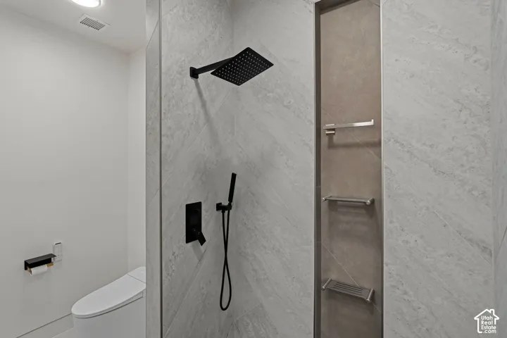 Walk-in shower with a matte black rain shower head and handheld sprayer