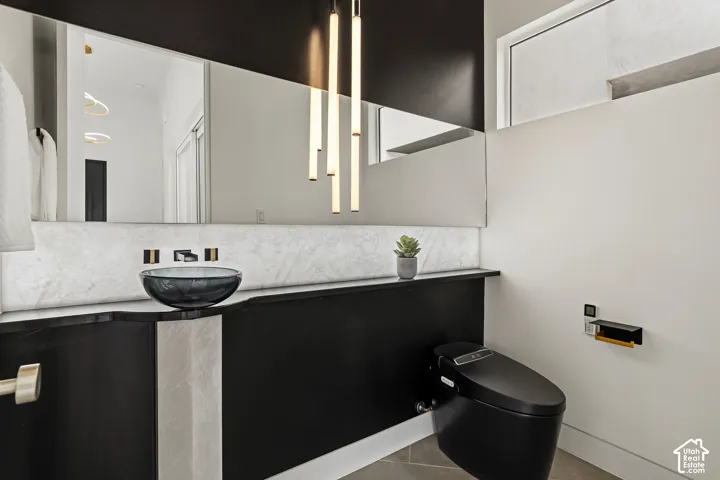 Floating vanity with a vessel sink, full-width mirror, wall-mounted fixtures, modern pendant lighting, and a black toilet