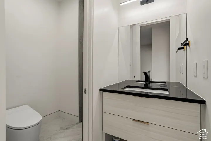 Integrated vanity with a black countertop, modern black faucet, and light wood-finish cabinetry