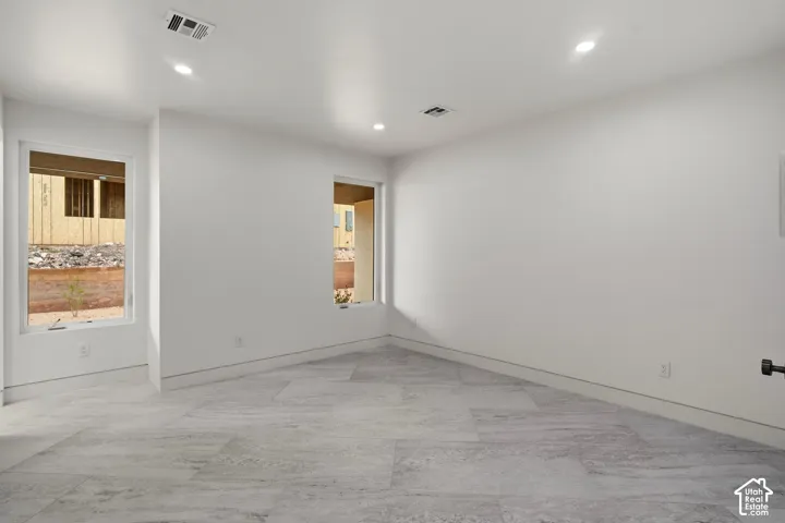 Neutral wall finishes, recessed lighting, and large format tile flooring