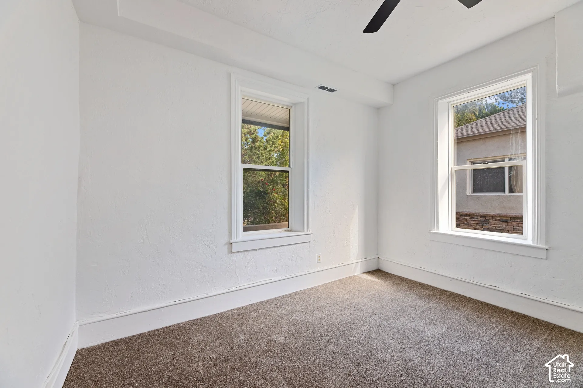 Main House Master Main Floor Bedroom with Two windows with white trim, a ceiling fan, and light brown carpet