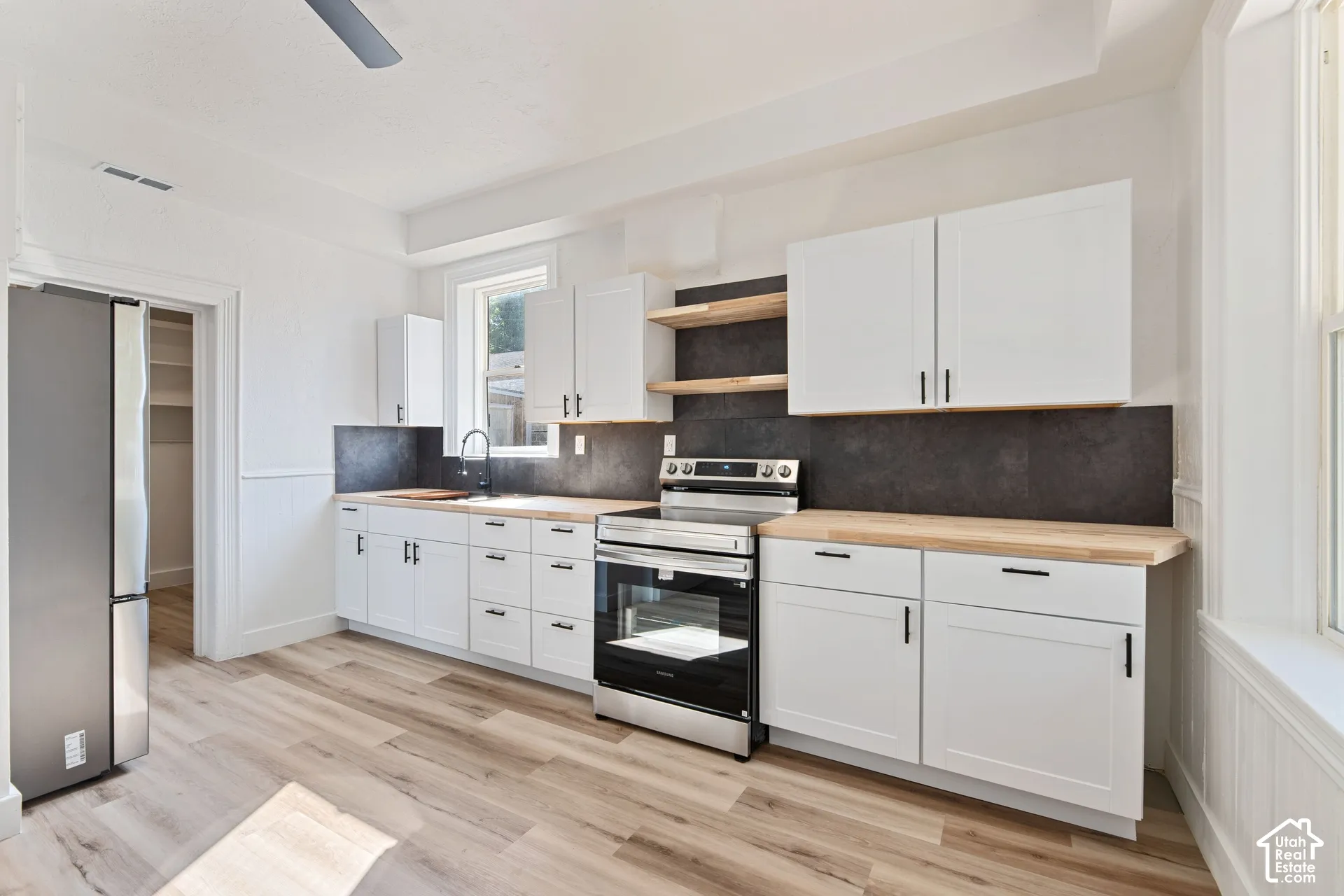 Main House Kitchen featuring new stainless steel appliances, white cabinetry, wood-finish countertops, and wood-finish flooring