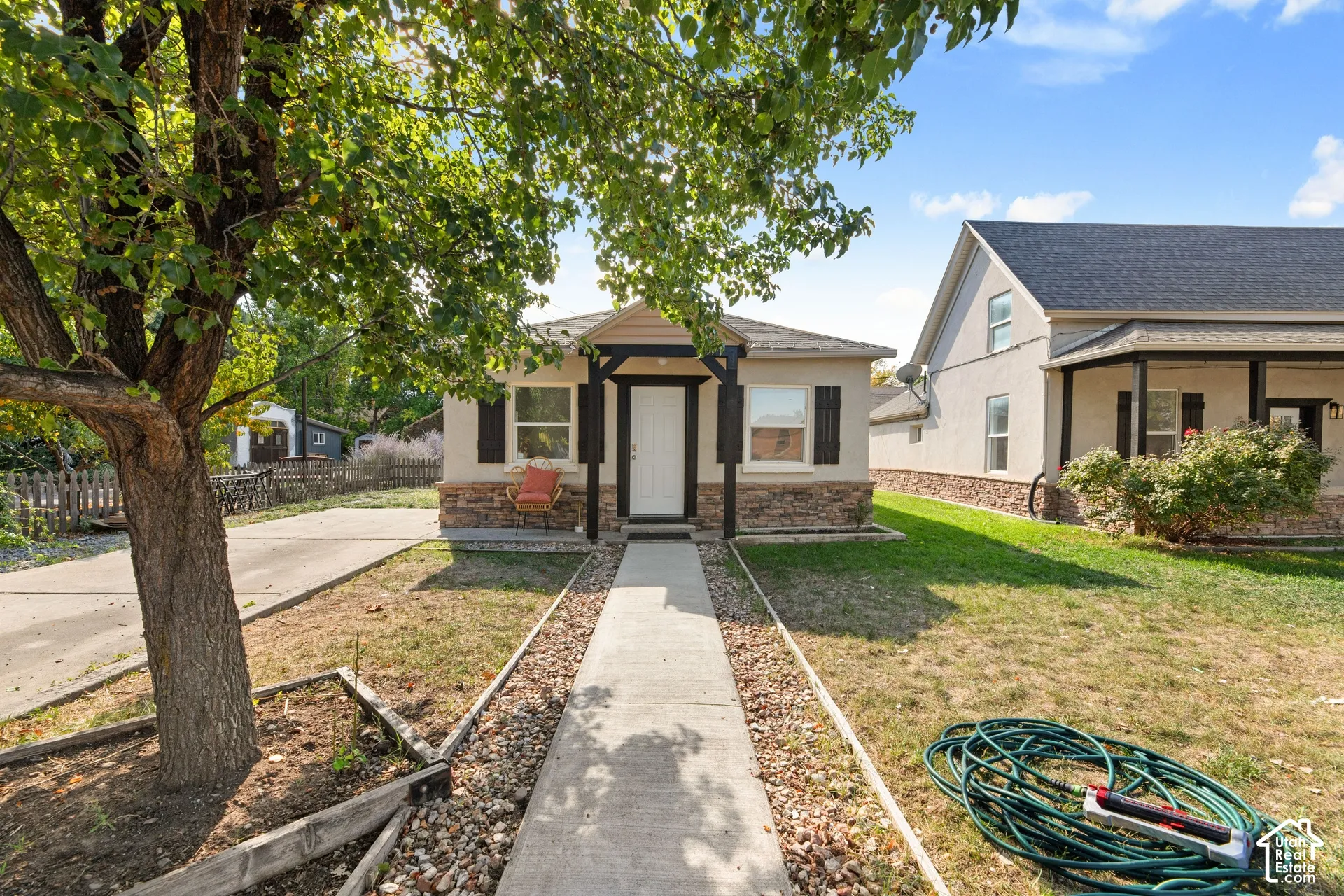 Single-story residence featuring a stone accent foundation, front porch with dark columns, and a concrete pathway