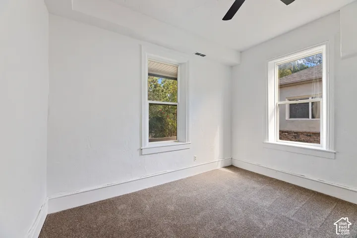 Main House Master Main Floor Bedroom with Two windows with white trim, a ceiling fan, and light brown carpet