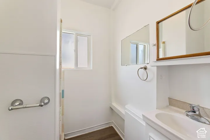 ADU Bathroom featuring a single vanity with a ceramic sink, a chrome faucet, a wooden framed mirror, and a frosted window