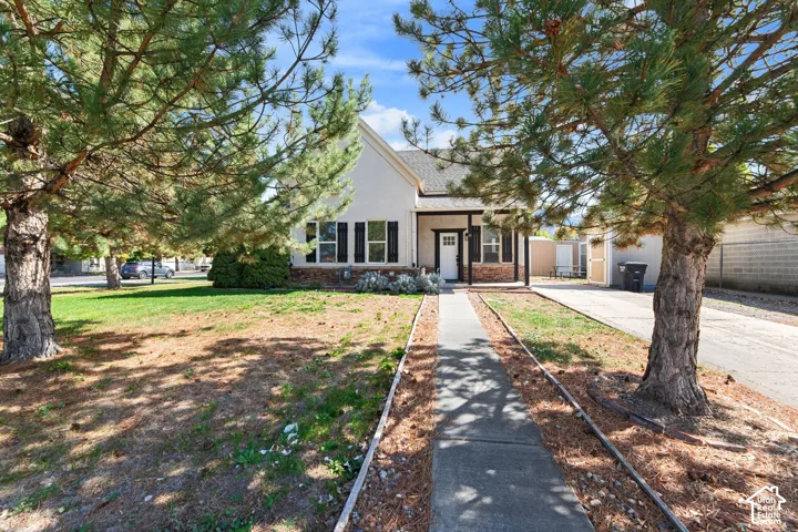 Stucco exterior with stone accent, covered front porch, front entry door, and a concrete walkway