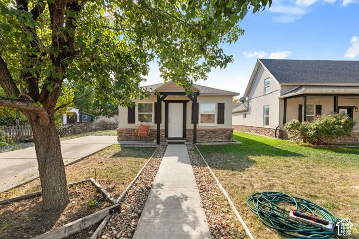Single-story residence featuring a stone accent foundation, front porch with dark columns, and a concrete pathway