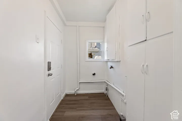 ADU Laundry Room with White cabinetry, wood-finish flooring, white paneled door with exit to backyard, and a small window