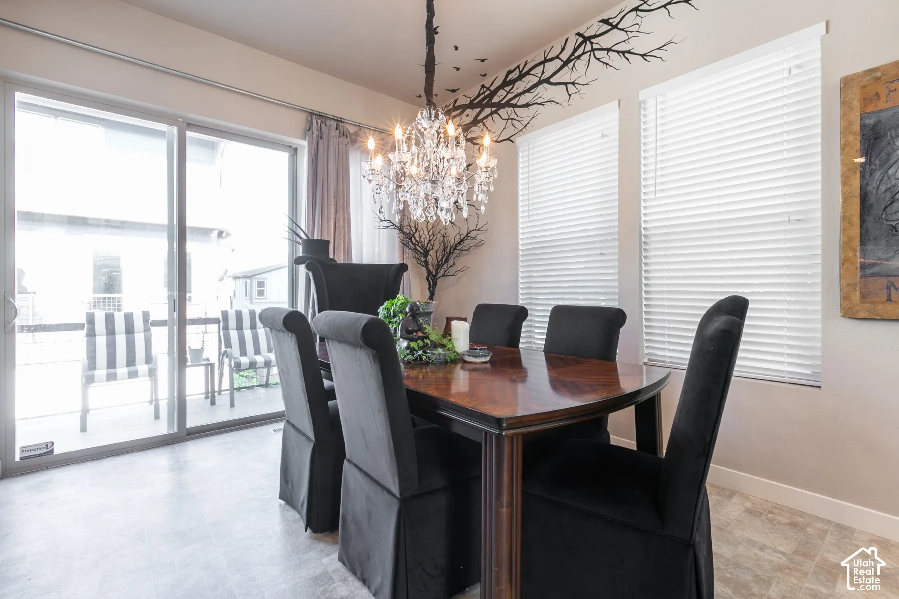 Sliding glass patio door with an adjacent window, a crystal chandelier, and tile flooring